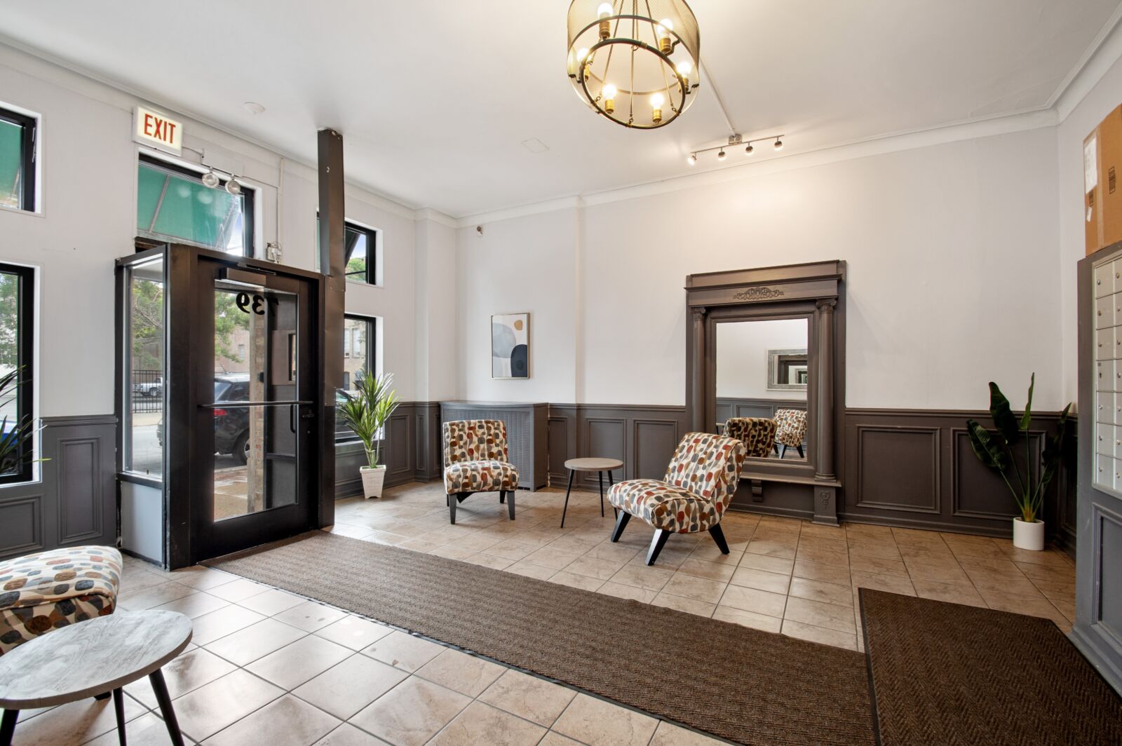 Lobby with tile flooring, statement chandelier, patterned chairs, and large framed mirror near en...