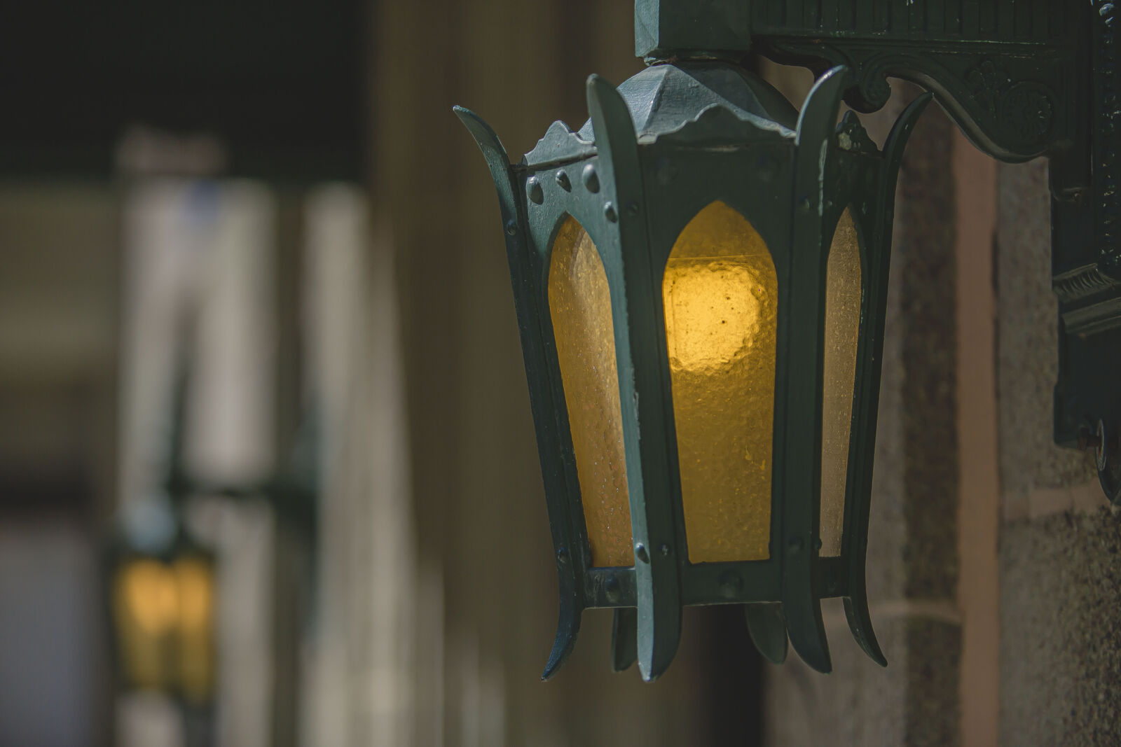 A close-up of a vintage green lantern-style light fixture with a warm yellow glow, mounted beside...