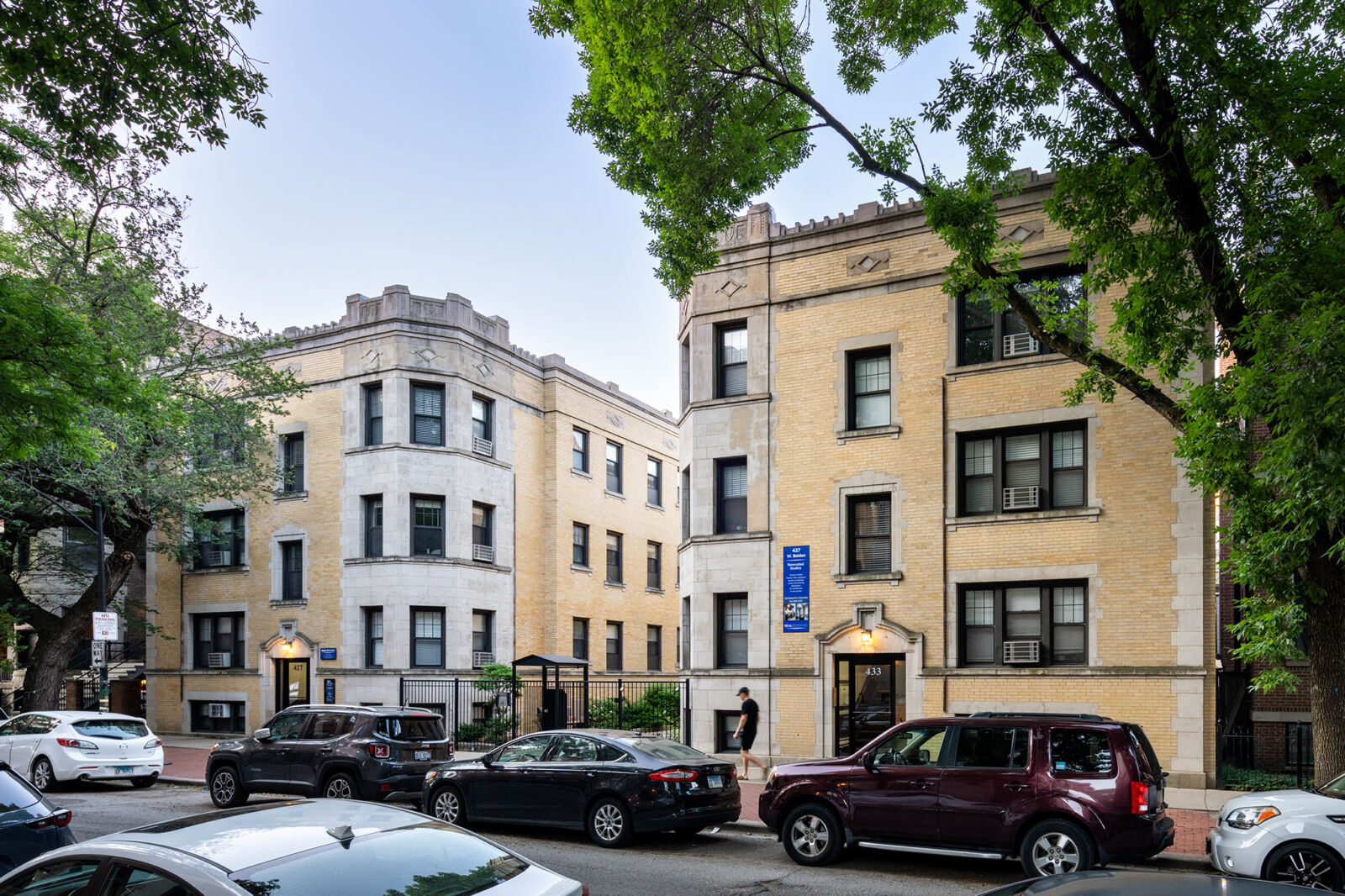 Angled view of vintage yellow brick courtyard apartment buildings with limestone trim and decorat...