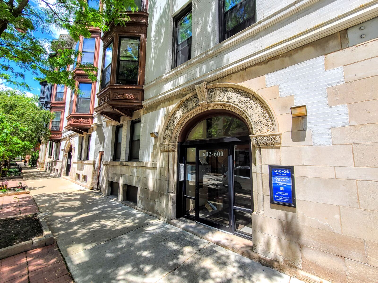 Tree-lined sidewalk at 600–606 West Surf Street in Chicago’s Lakeview neighborhood, with the orna...