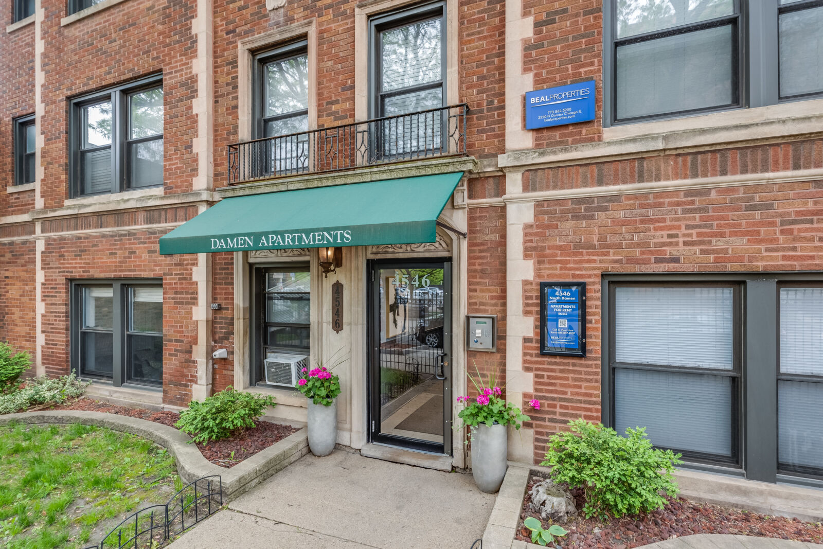 Front view of 4546 North Damen Avenue showing the green “Damen Apartments” awning, tan stone trim...
