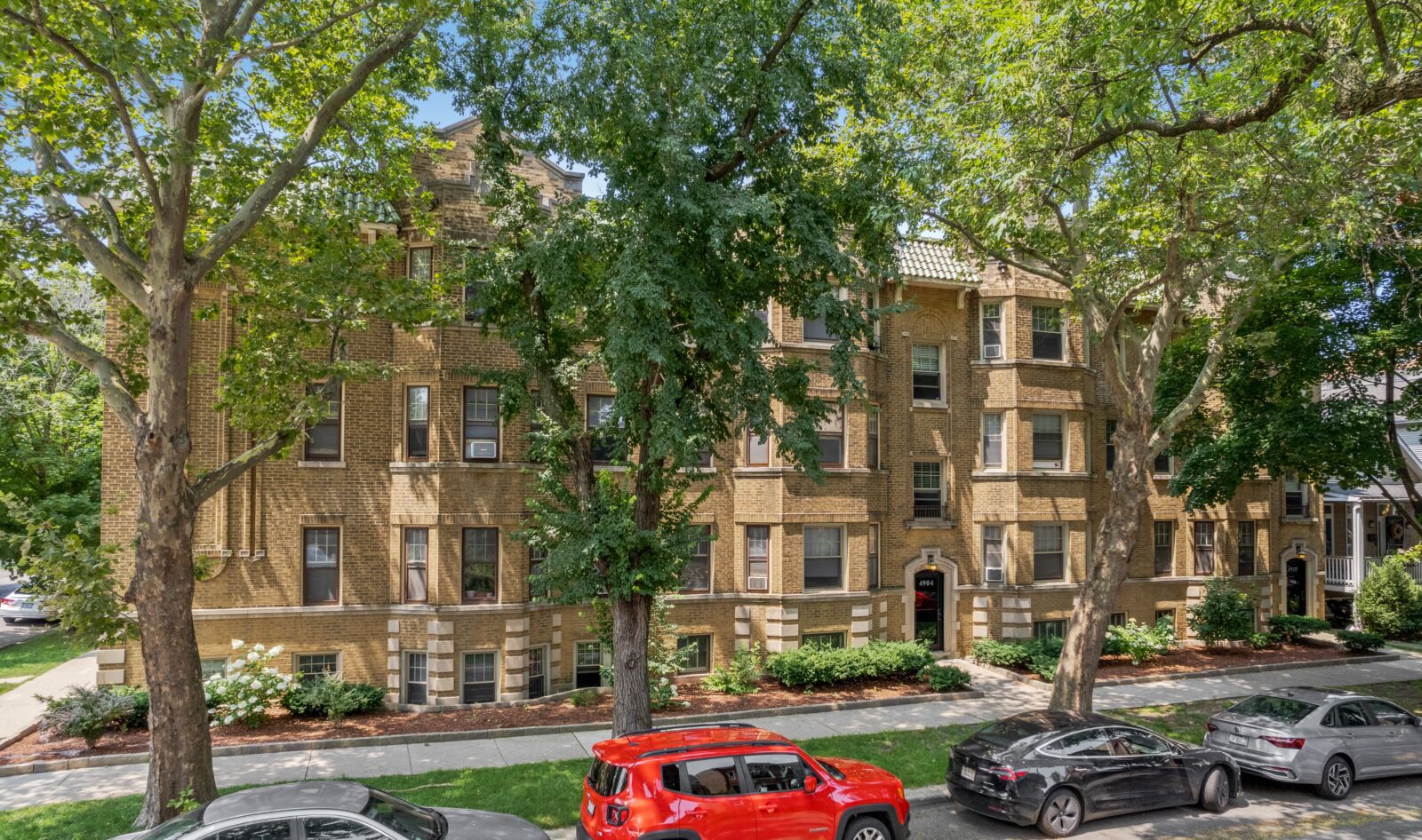 A four-story yellow brick apartment building at 4910 North Damen Avenue, part of the 2100 West Ai...