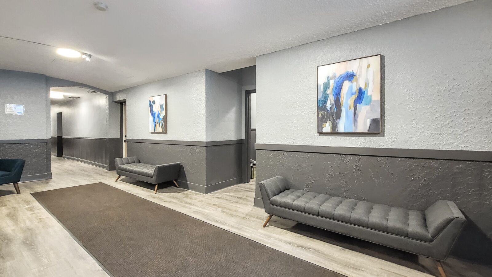 Interior corridor at 4851 N Damen Ave (Lincoln Square) with gray benches, abstract artwork, and l...